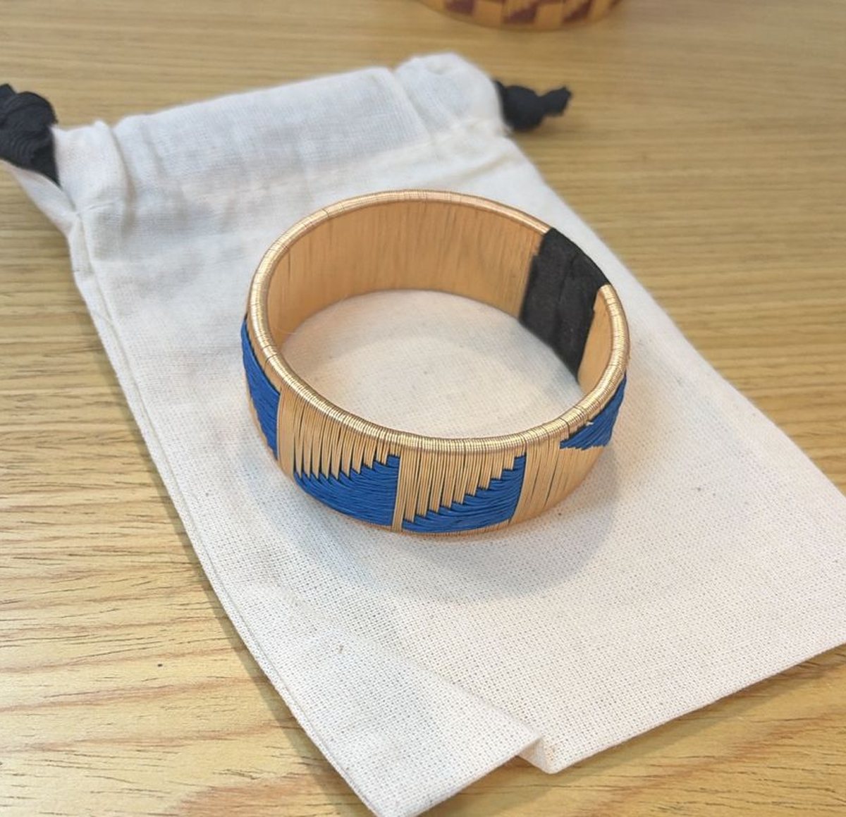 A blue and gold cuff resting on its cotton pouch